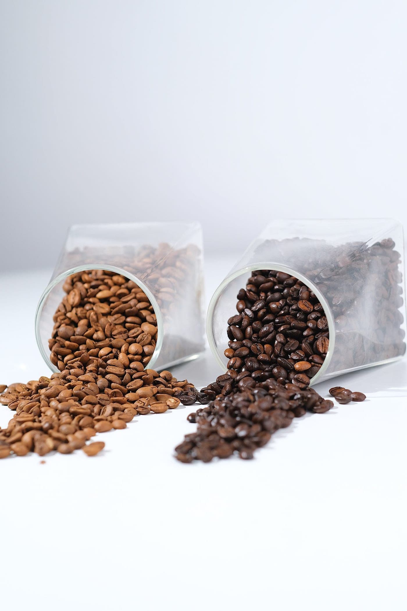 Coffee beans spilling from two glass jars